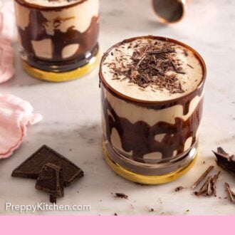 Pinterest graphic of two chocolate coated glasses of mudslides with shaved chocolate on top.