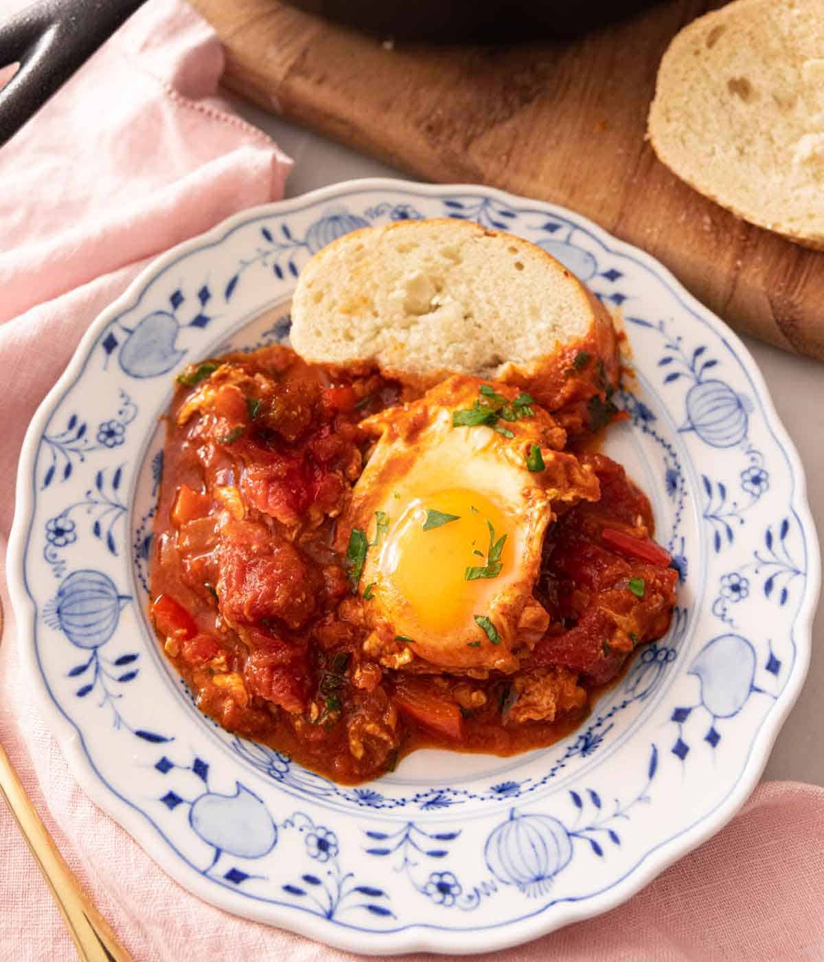 A plate of shakshuka with a slice of bread.