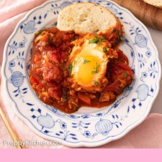 Pinterest graphic of a plate of a serving of shakshuka with a slice of French bread.