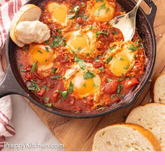 Pinterest graphic of a skillet of shakshuka with bread and a serving spoon inside of the pan.