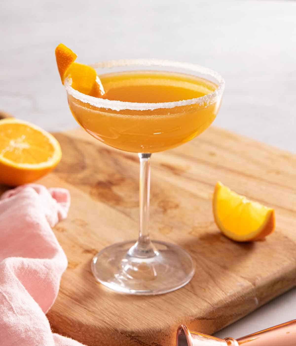 A sidecar cocktail with an orange peel garnish and sugar rim.