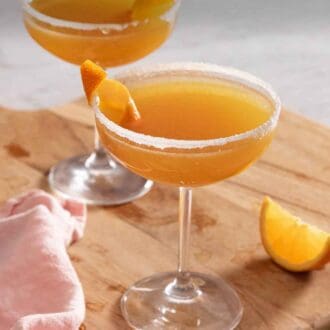 Pinterest graphic of two glasses of sidecar cocktails on a serving board.