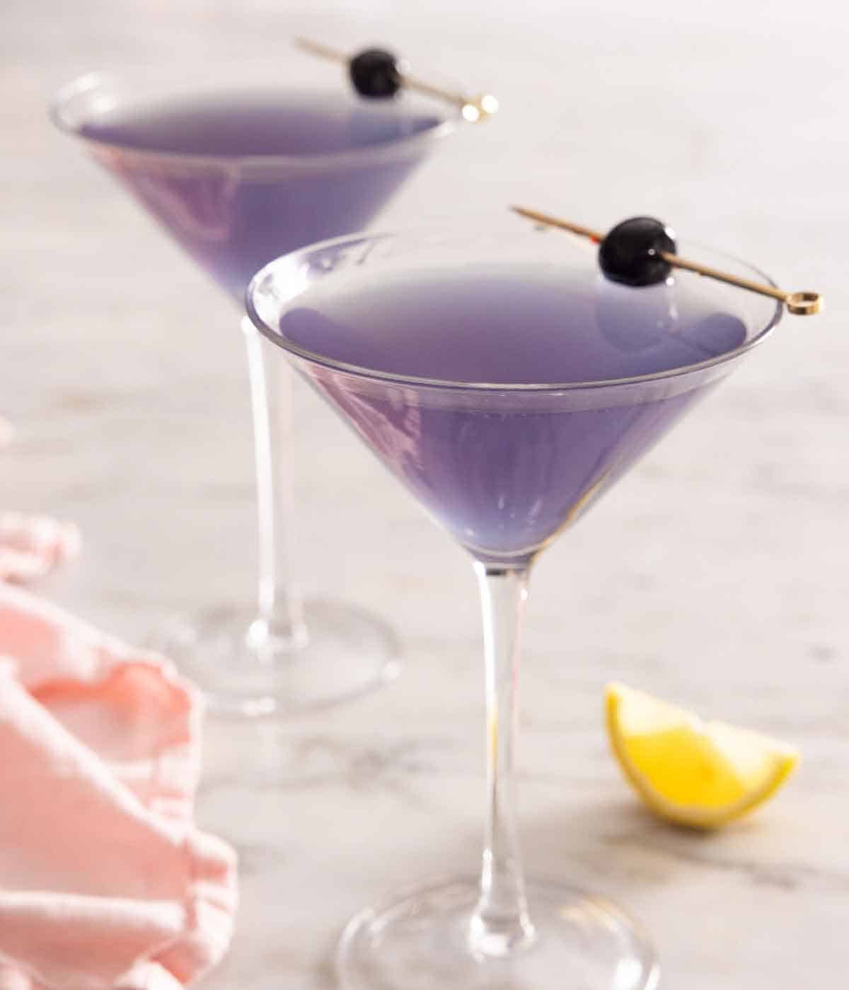 Two glasses of Aviation cocktail with cocktail cherry garnishes.