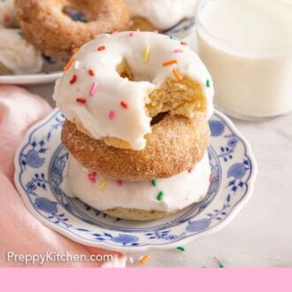 Pinterest graphic of a plate with three baked donuts stacked by a glass of milk.