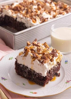 A square piece of better than sex cake by a cup of milk.