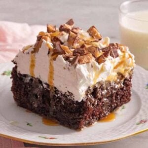 A plate with a square slice of better than sex cake with caramel dripping down.