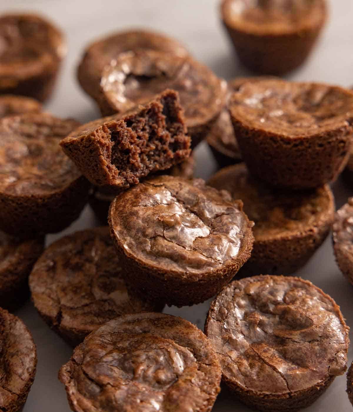 A pile of brownie bites with one bitten in half.