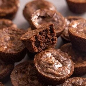 Multiple brownie bites stacked on top of each one with one on top with a bite taken out.