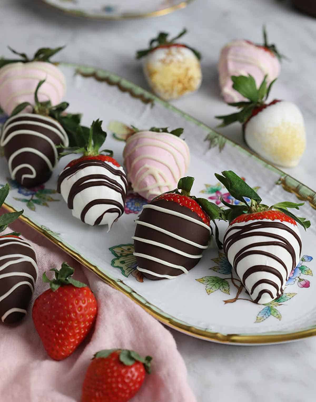 A platter of chocolate covered strawberries with different chocolate coatings.