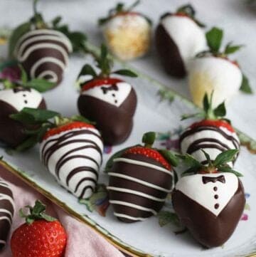 A platter of chocolate covered strawberries decorated in different ways.