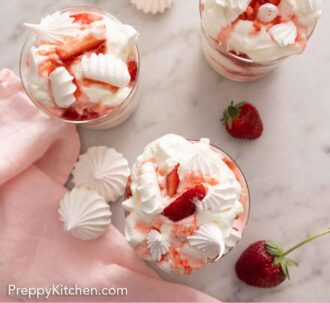 Pinterest graphic of an overhead view of three Eton mess desserts with meringues and strawberries around.