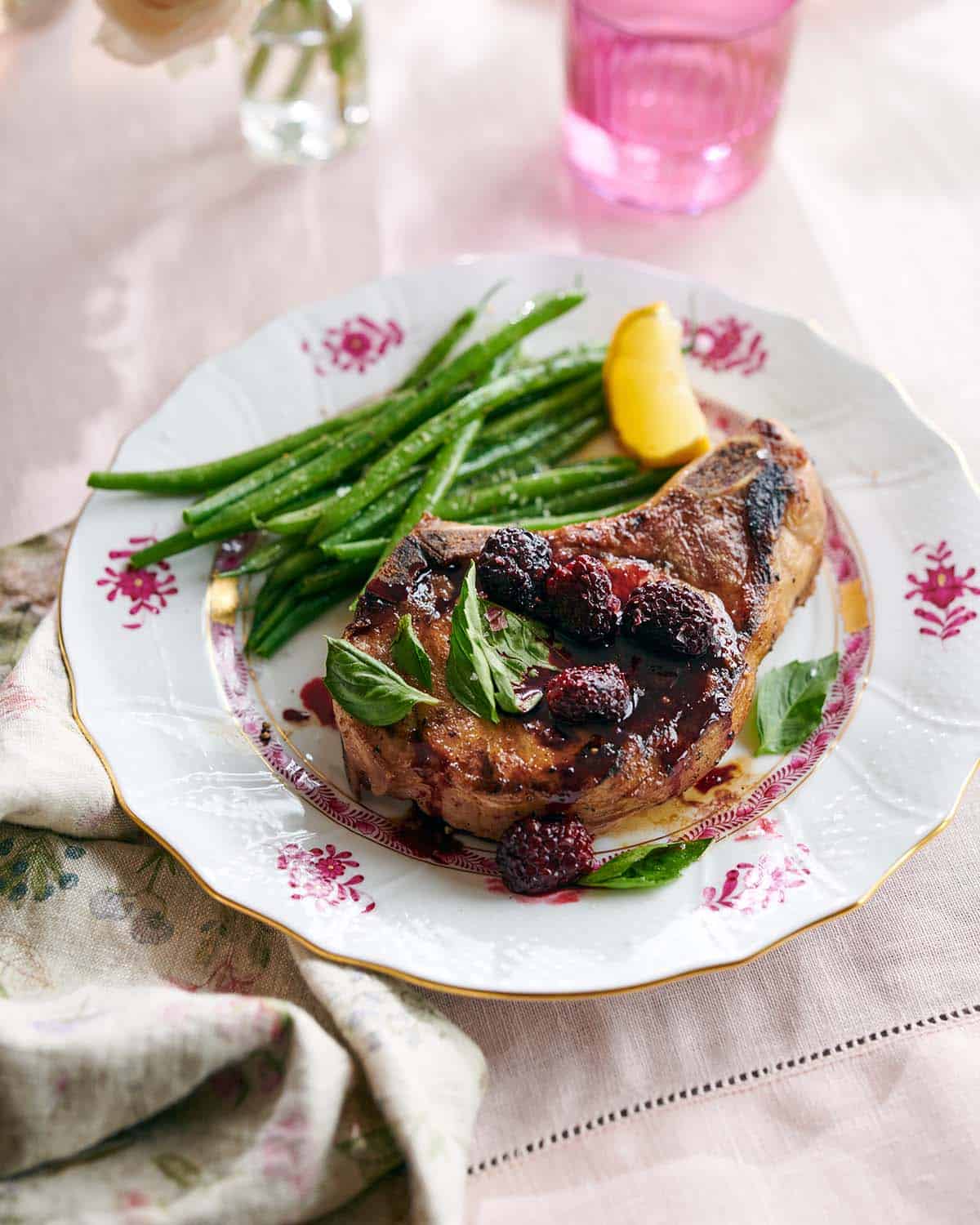 A porkchop on a plate with a blackberry balsamic reduction.
