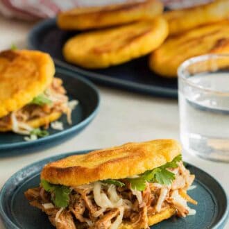 Pinterest graphic of arepa stuffed with shredded meat on a plate.
