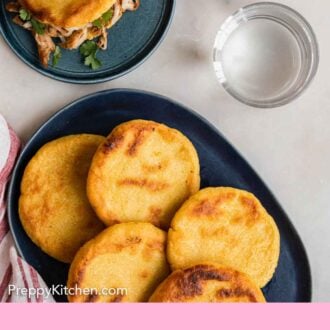 Pinterest graphic of an overhead view of a platter of arepas with a plate with one.