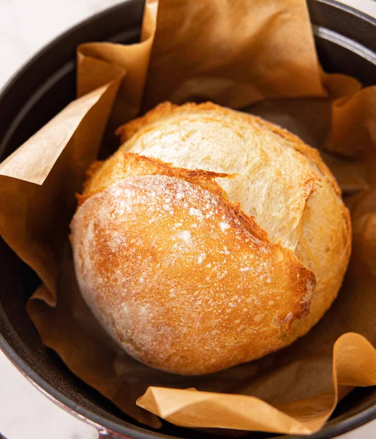 A dutch oven with an artisan bread with parchment paper.