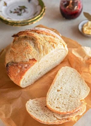 A boule of artisan bread with two slices cut in front.