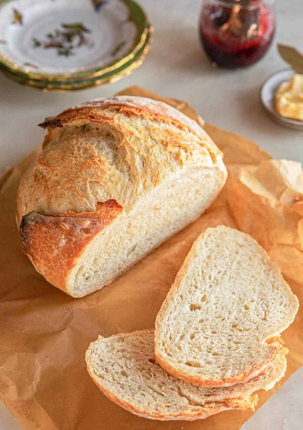 A boule of artisan bread with two slices cut in front.