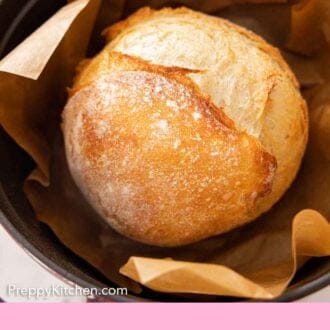 Pinterest graphic of a loaf of artisan bread in a dutch oven lined with parchment paper.