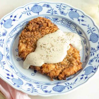 Angled view of a plate of chicken fried steak with gravy.