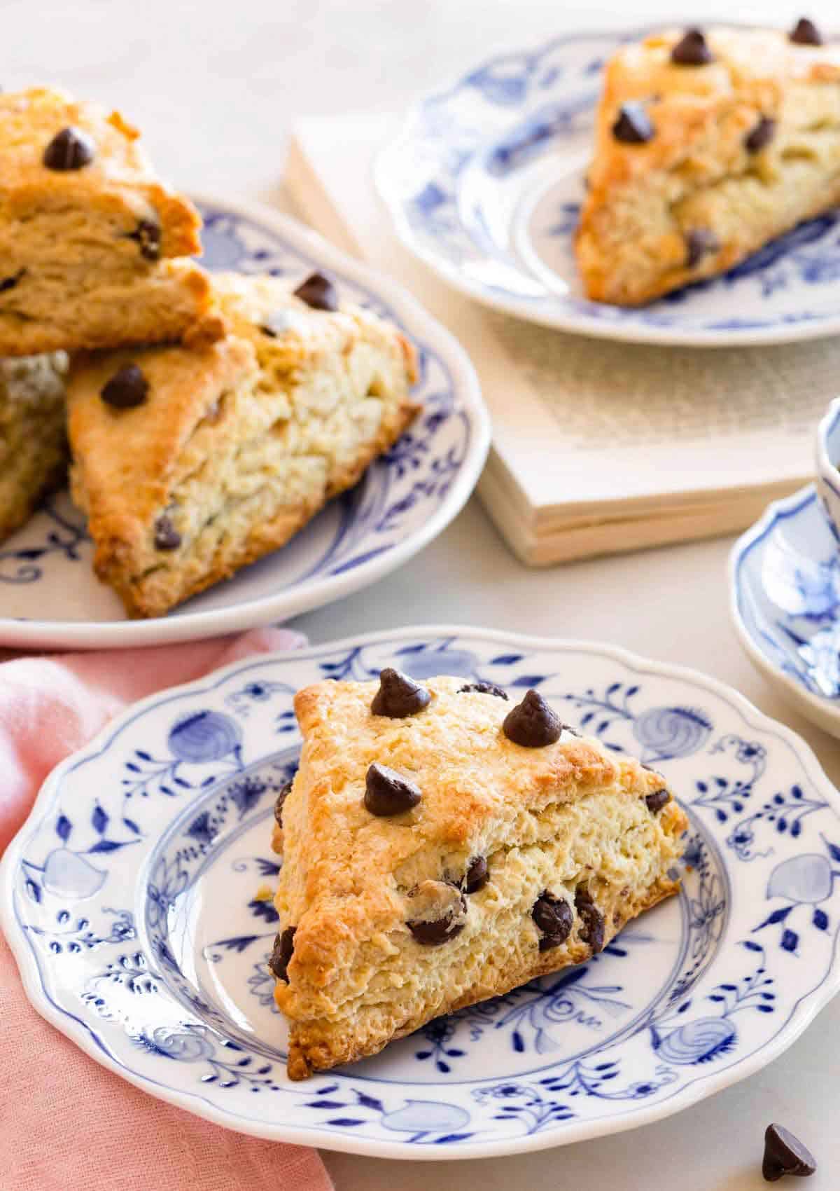 A chocolate chip scone on a plate with more in the background.