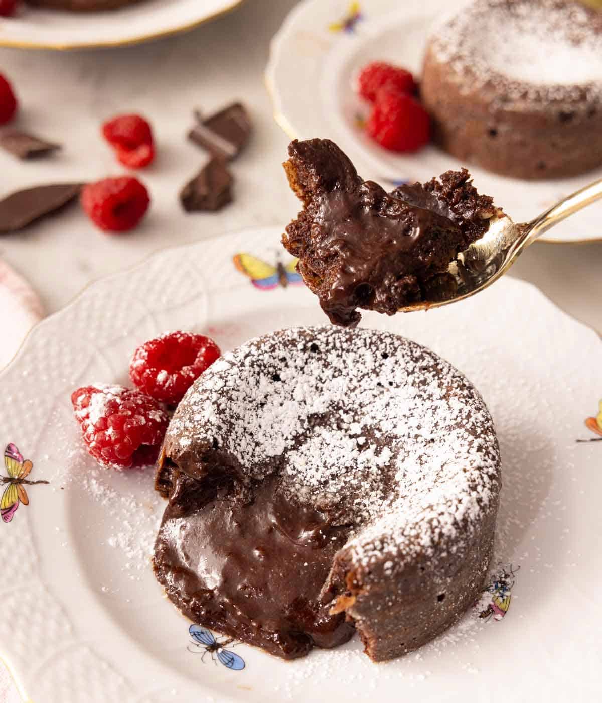 A chocolate lava cake on a plate with a spoonful lifted up.