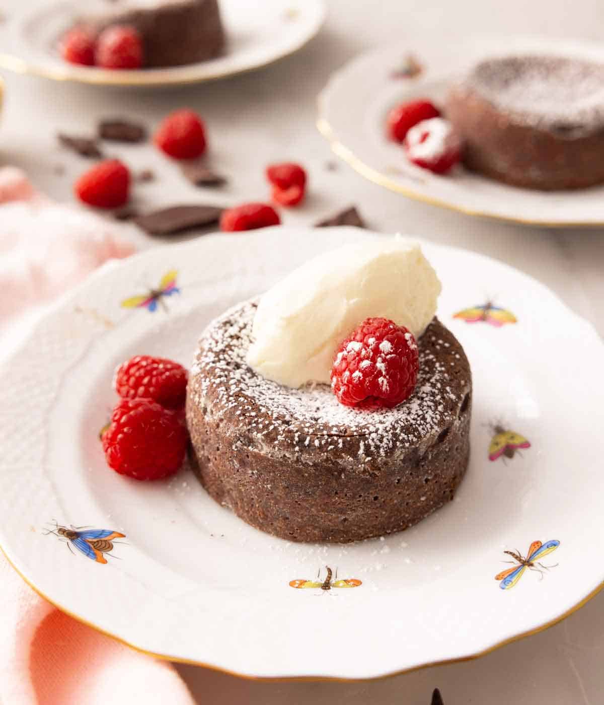 A chocolate lava cake with raspberries, a scoop of ice cream, and powdered sugar on top.