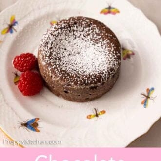 Pinterest graphic of a plate of chocolate lava cake with two raspberries and powdered sugar as garnish.