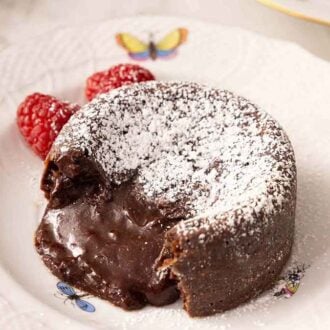 A plate with an opened chocolate lava cake with powdered sugar on top.