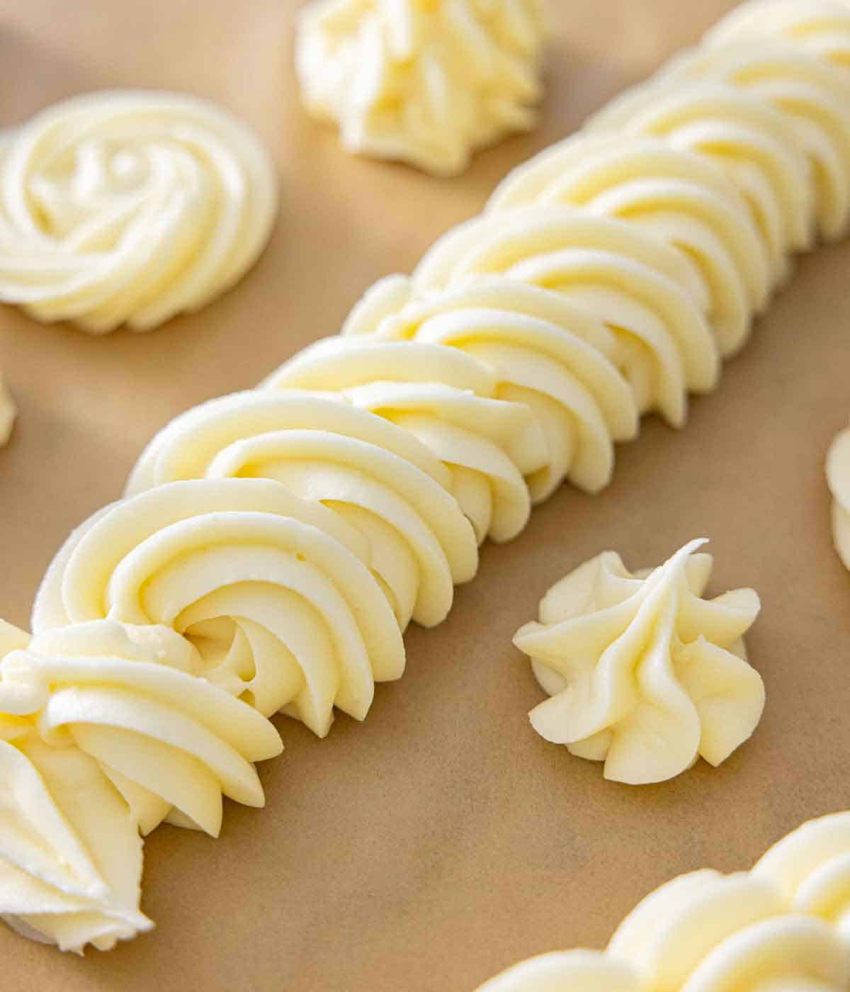 A parchment with different styles of cream cheese frosting piped.