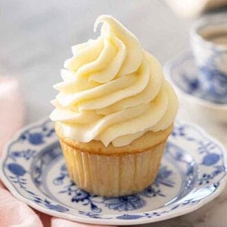 A cupcake with cream cheese frosting piped in a tall triangle shape.