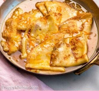 Pinterest graphic of a skillet with crepe suzette with orange zest on top.
