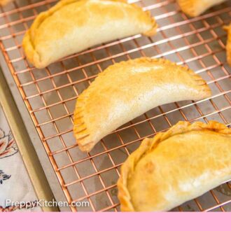 Pinterest graphic of empanadas cooling on a wire rack.