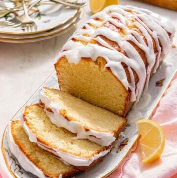 A platter with a loaf of lemon pound cake with three slices cut.