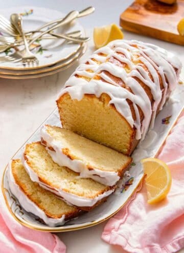 A platter with a loaf of lemon pound cake with three slices cut.