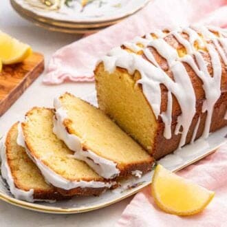 A platter of lemon pound cake with three slices cut with lemon wedges around it.
