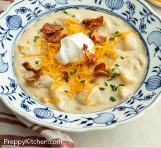 Pinterest graphic of a bowl of potato soup with sour cream, cheese, bacon, and chives on top.