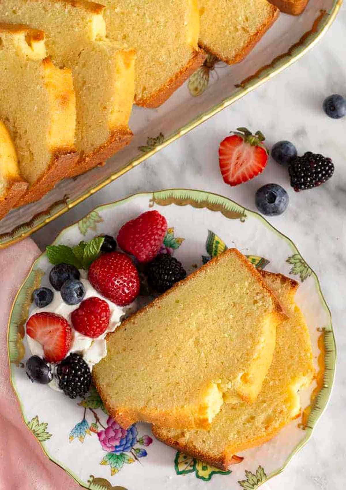 Overhead view of a plate with two slices of pound cake with berries and whipped cream.