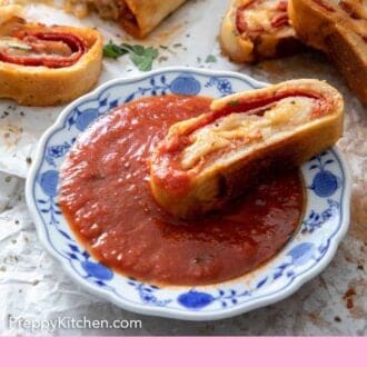 Pinterest graphic of a plate of sauce with a piece of stromboli dipped inside.