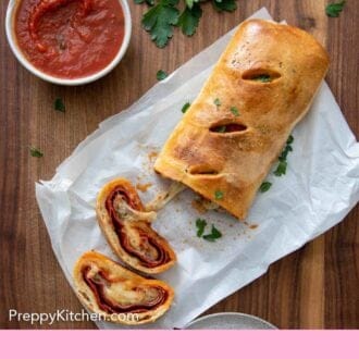 Pinterest graphic of an overhead view of stromboli with two pieces cut by some herb garnish and sauce.