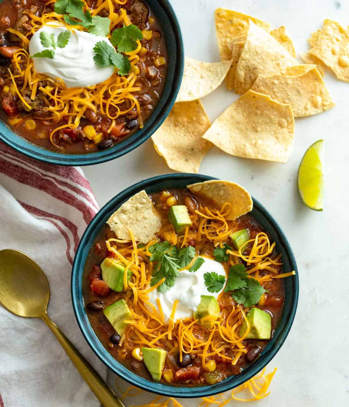 Overhead view of two bowls of taco soup with chips scattered around the bowls.