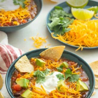 Pinterest graphic of bowls of taco soup with a plate of toppings on the side.