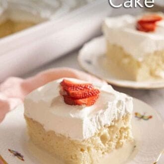 Pinterest graphic of a square slice of tres leches cake on a plate with sliced strawberries on top.