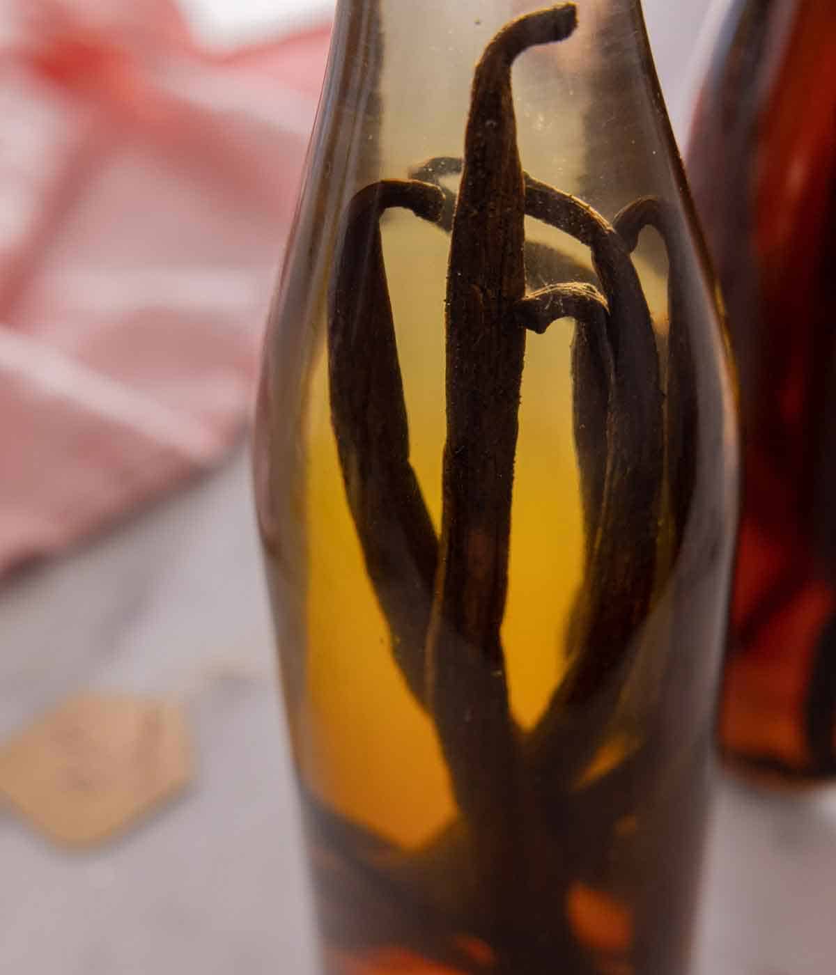 Close up of vanilla beans inside of a bottle of homemade vanilla extract.