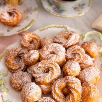 Pinterest graphic of a plate with zeppole with powdered sugar dusted on top.
