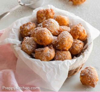 Pinterest graphic of a parchment-lined basket of zeppole with sugar dusted.