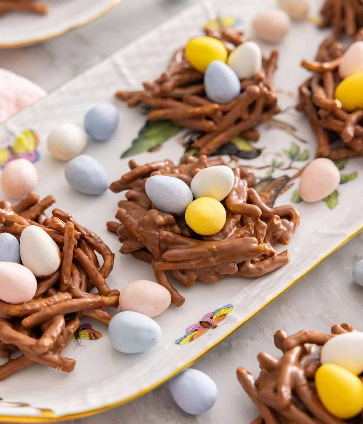 A platter of birds nest cookies with candy eggs scattered around.