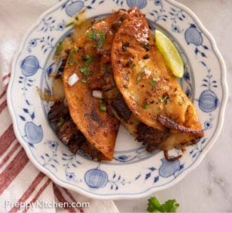 Pinterest graphic of a plate with two birria tacos with a lime wedge.