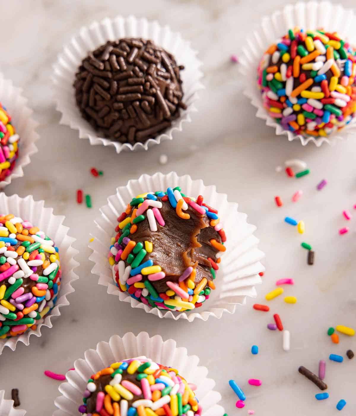 Multiple brigadeiros with one with a bite taken out of it.