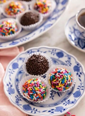 A plate with three brigadeiros with sprinkles coating them,
