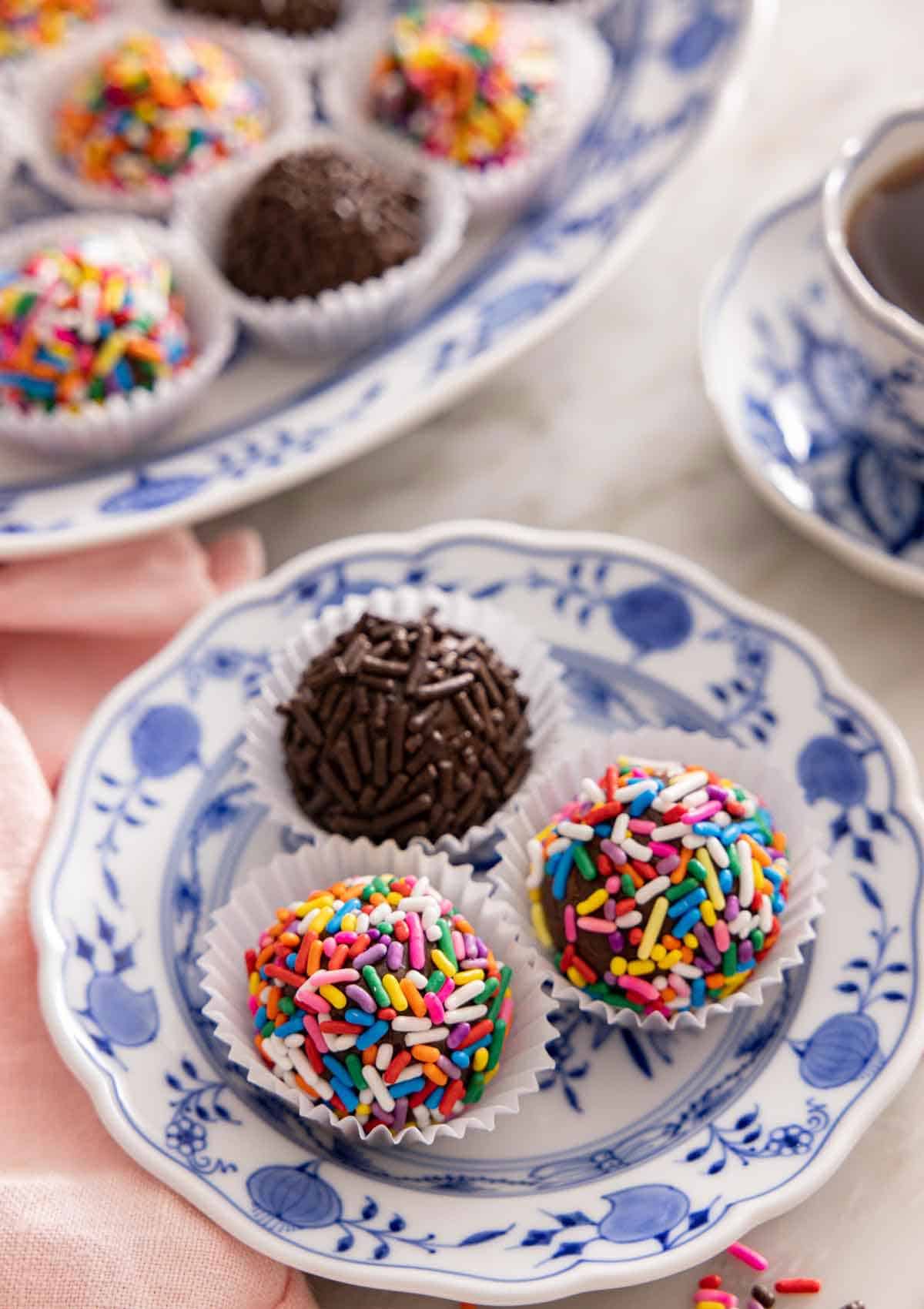 A plate with three brigadeiros with sprinkles coating them,